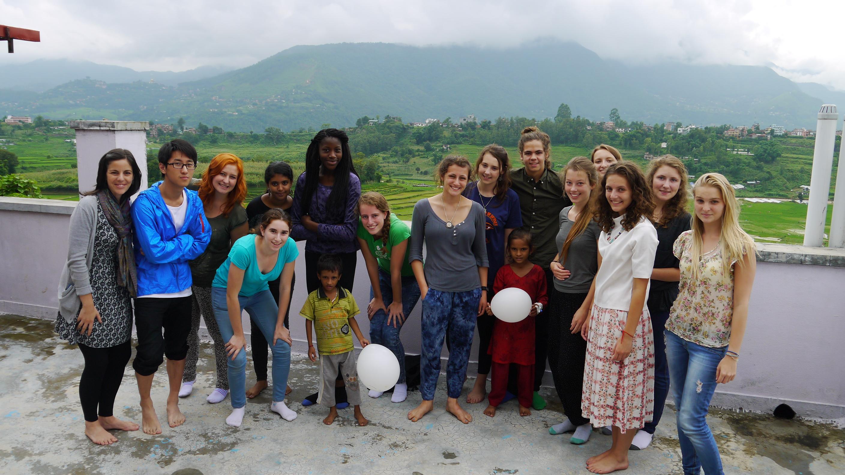 A large group of teenage community volunteers working in Nepal, take a group photo. Teenage volunteers doing work with children in Nepal, take a photo with children.